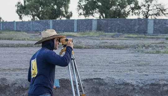 Ingeniero utilizando teodolito en el fraccionamiento de terrenos Bosque Central ubicado en Aguascalientes desde cerca