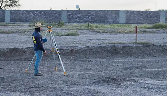 Ingeniero utilizando teodolito en el fraccionamiento de terrenos Bosque Central ubicado en Aguascalientes desde lejos